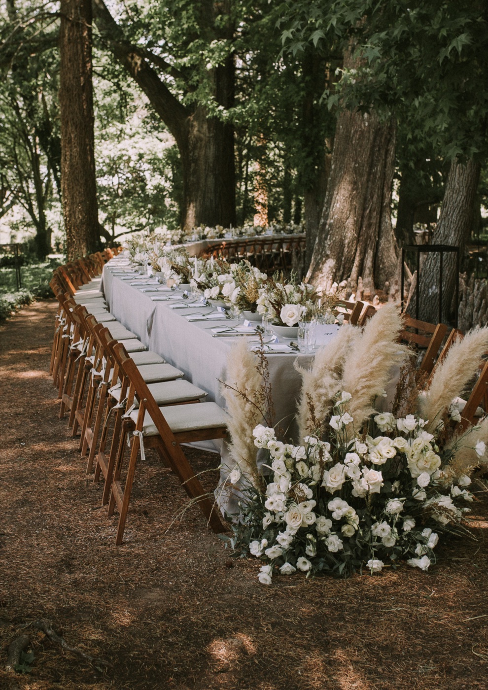 Baby shower dans un jardin : table basse en bois, coussins et fleurs